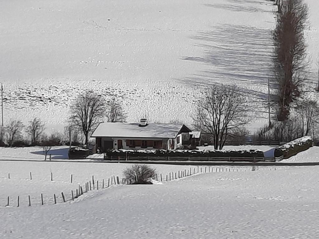a house in a snow covered field with a fence at Haus Kreuzboden in Hundsdorf