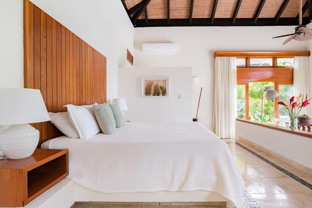 1 dormitorio con cama blanca y ventana en Ileverde 21 - Private garden Bungalow, en Punta Cana