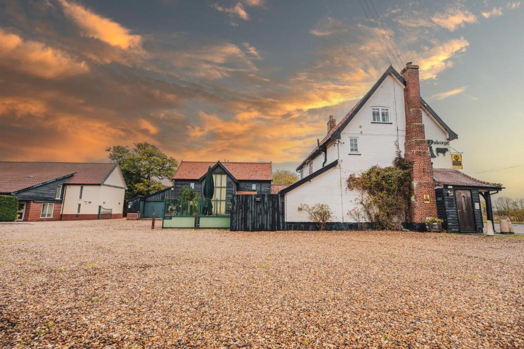 a house on a gravel field with a cloudy sky at The Auberge in Yaxley