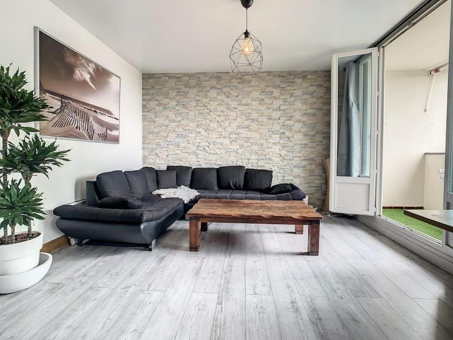 uma sala de estar com um sofá preto e uma mesa de centro em Appart Crystal Lyon Caluire et parkings em Caluire-et-Cuire