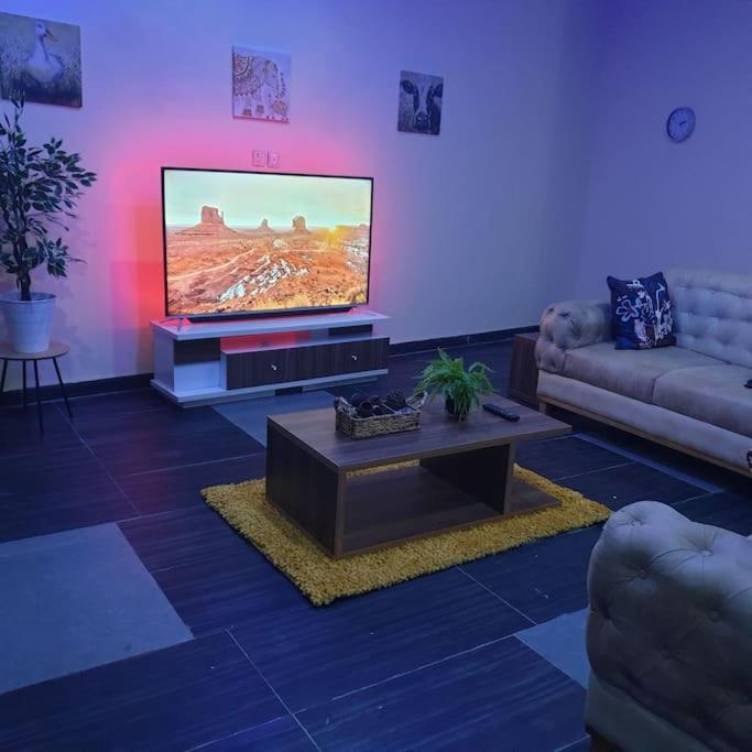 ein Wohnzimmer mit Fernseher, Couch und Tisch in der Unterkunft ORCHID House , Orchid Road , Lekki , Stylish 3BDR Terrace Duplex Free WiFi DSTV in Lekki