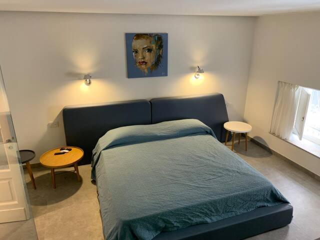 een slaapkamer met een blauw bed en een schilderij aan de muur bij SUITE Nobile in Catania