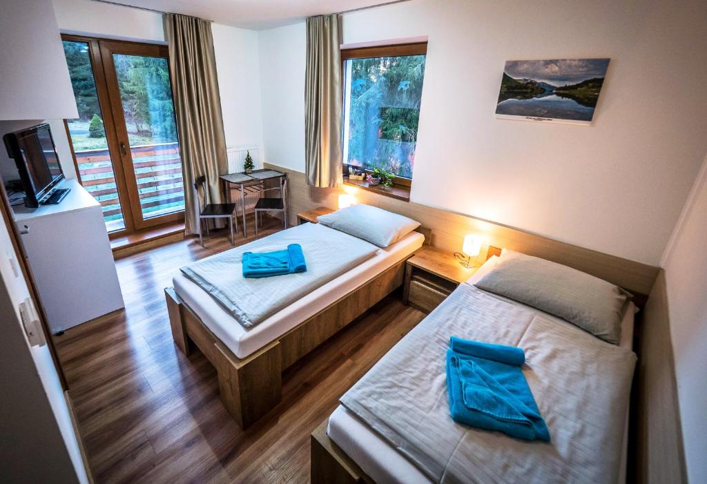 Cette chambre comprend deux lits et une télévision. dans l'établissement Apartmanovy Dom Vila Vista, à Demänovská Dolina