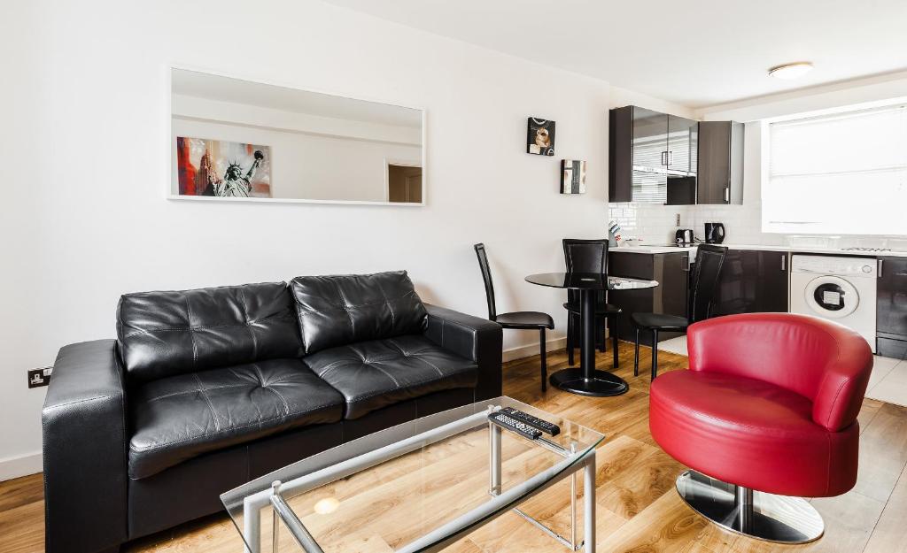 a living room with a black couch and a red chair at Parnell Apartments in Dublin