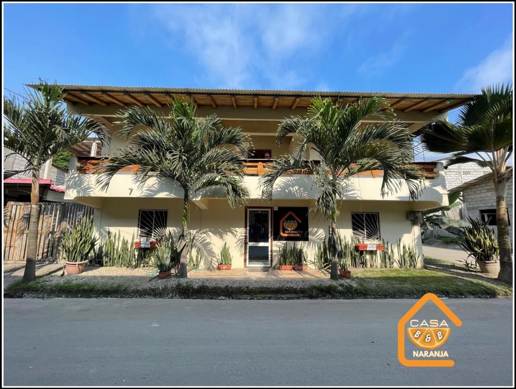 a building with palm trees in front of it at Bed and Breakfast La Casa Naranja in Olón