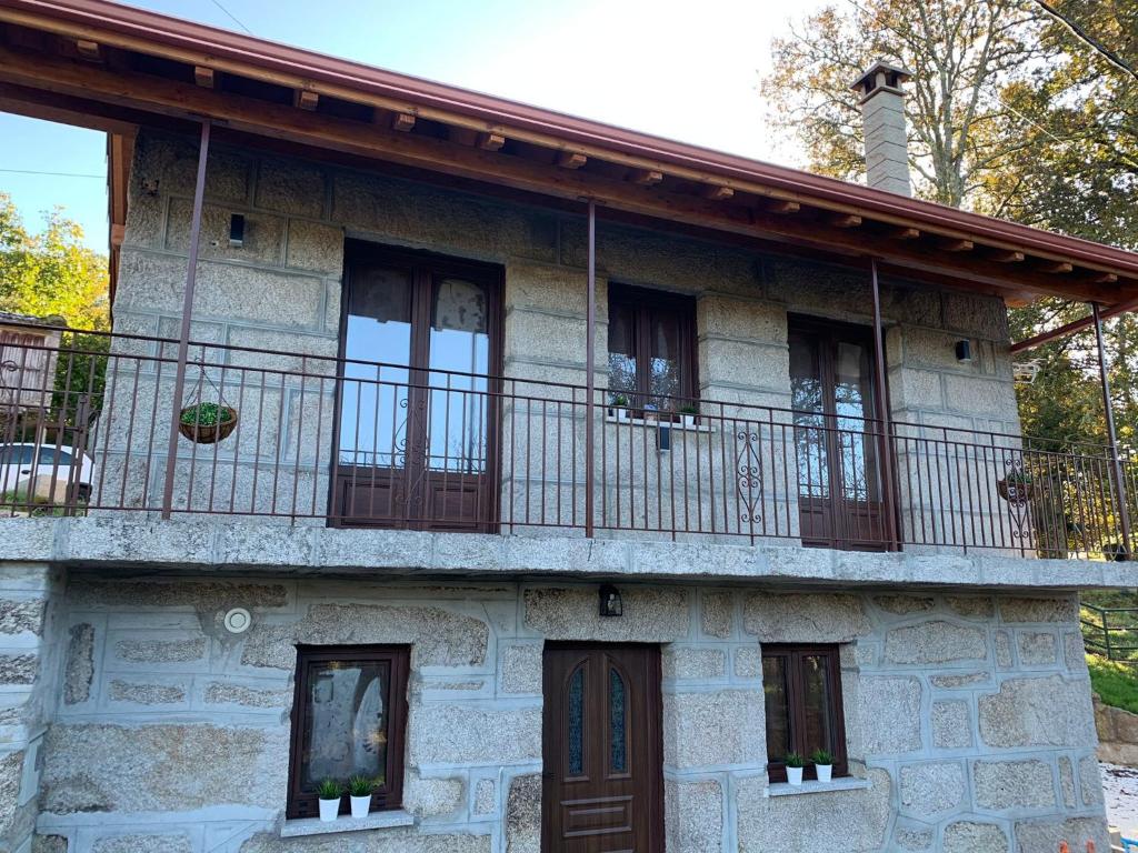 una vecchia casa in pietra con balcone di CASA TIO HERMINIO a O Irixo