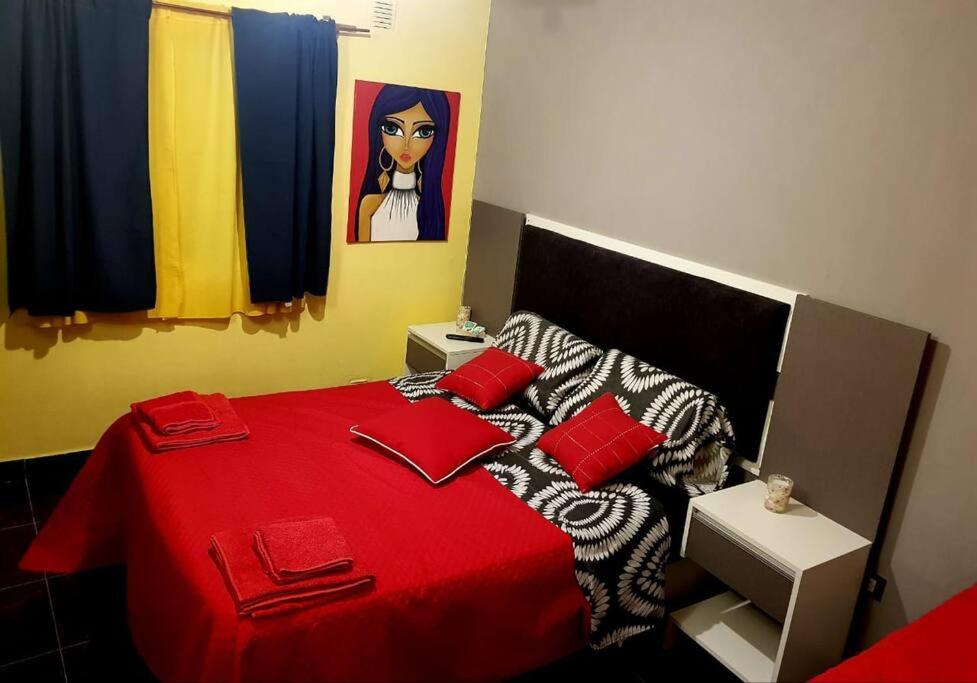 1 dormitorio con cama roja y almohadas rojas en Departamento moderno x día en Neuquén