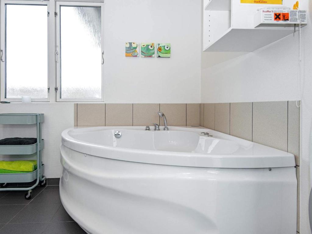 un bagno bianco con vasca e lavandino di Three-Bedroom Holiday home in Ulfborg 16 a Fjand Gårde