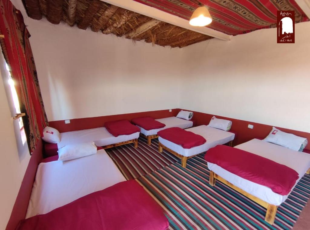 Habitación con 4 camas y cojines rojos. en Gite Agham Azegagh - Timimoun, 