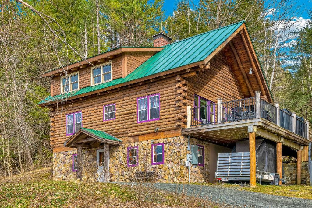 Cabaña de madera con techo verde y balcón en Wood Road Retreat, en Quechee