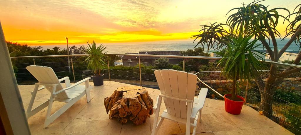 two chairs and a table on a balcony with a sunset at Beachwood Camps Bay in Cape Town