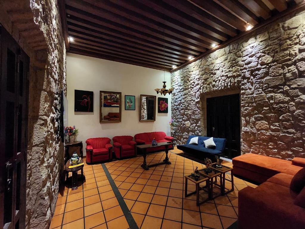 a living room with red couches and a stone wall at Casa monarca in Morelia