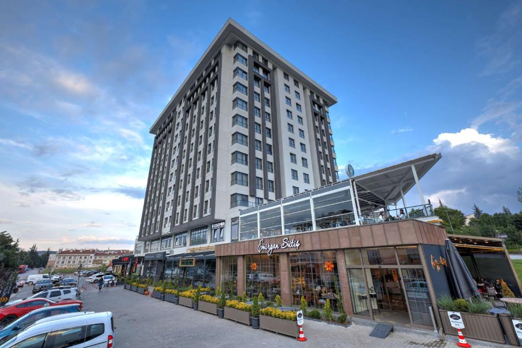 wysoki biały budynek z samochodami zaparkowanymi na parkingu w obiekcie Nova Vista Deluxe & Suites a Member of Radisson Individuals w mieście Eskişehir