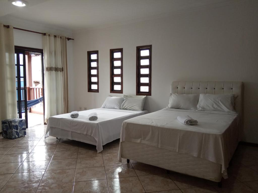 two beds in a room with two windows at Casa da Fê in São Sebastião