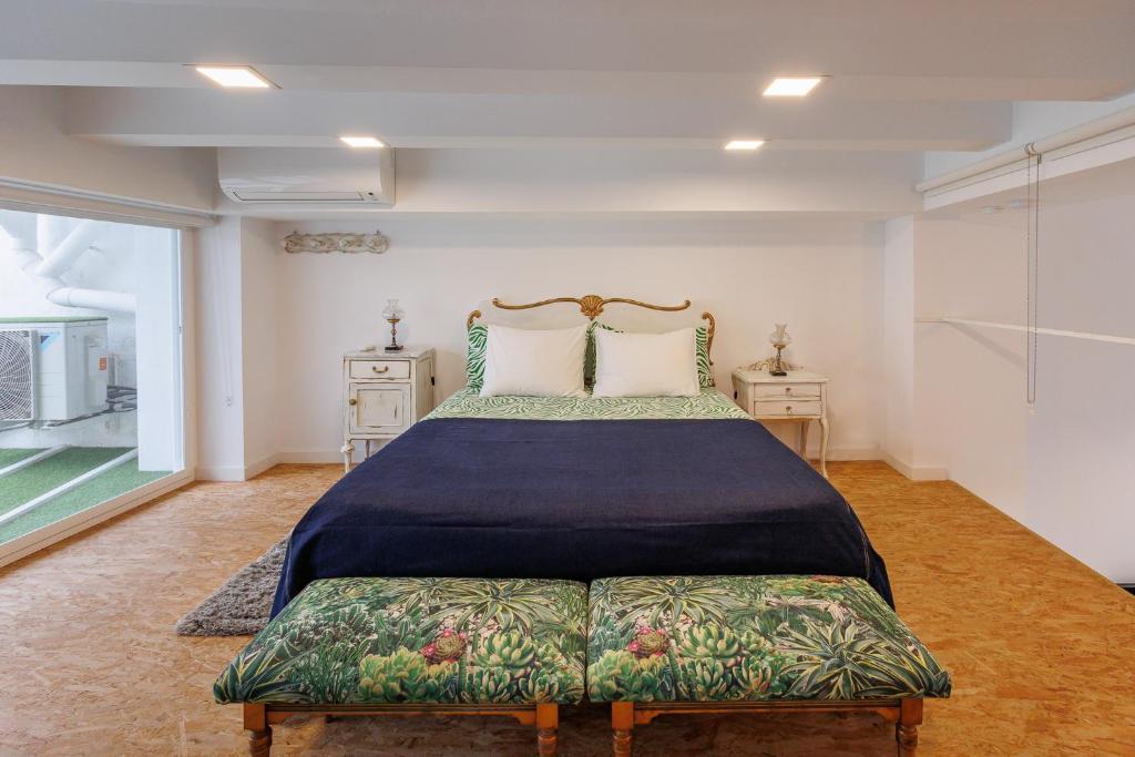 a bedroom with a bed and two tables and a window at Loft con mucha luz en el centro Barrio Ruzafa in Valencia