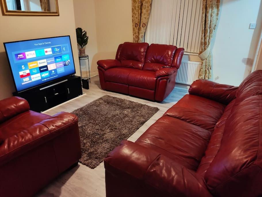 een woonkamer met rode lederen meubels en een flatscreen-tv bij Cheerful 2-bedroom home with off street parking in Blackpool