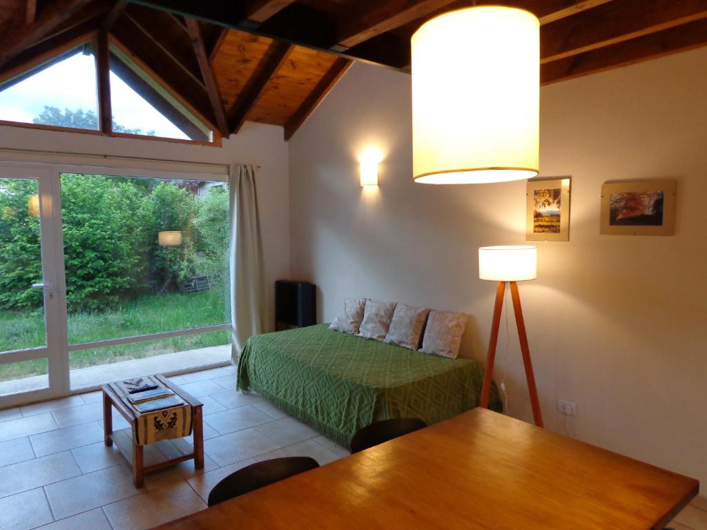 um quarto com uma cama, uma mesa e uma janela em Casas con vista al Piltri em El Bolsón