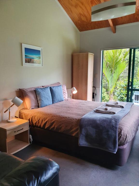 een slaapkamer met een groot bed en een groot raam bij Kauri Coast TOP 10 Holiday Park in Kaihu