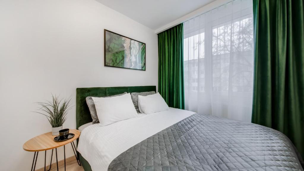 Schlafzimmer mit einem großen Bett und grünen Vorhängen in der Unterkunft Stylish Apartment in Zverynas in Vilnius