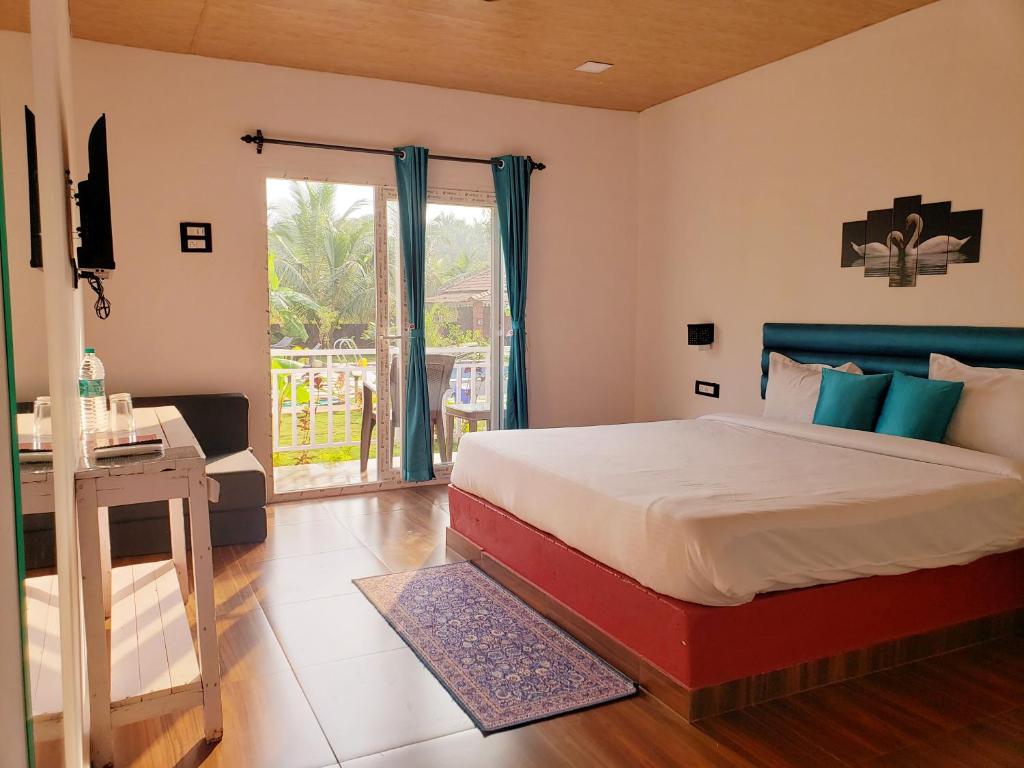 White Truffle Resort, Arambol في أرامبول: غرفة نوم بسرير ومكتب ونافذة
