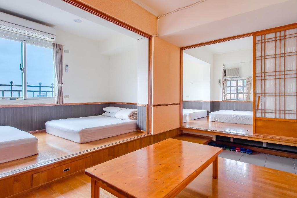 a room with two beds and a table and a mirror at Jiufen Kite Museum in Jiufen