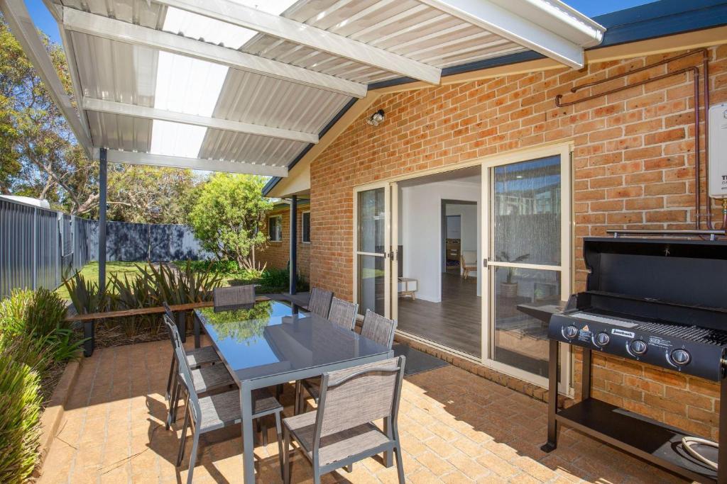 a patio with a grill and a table and chairs at Coastal Capers - Pet Friendly - 10 Mins Walk to Beach in Culburra Beach
