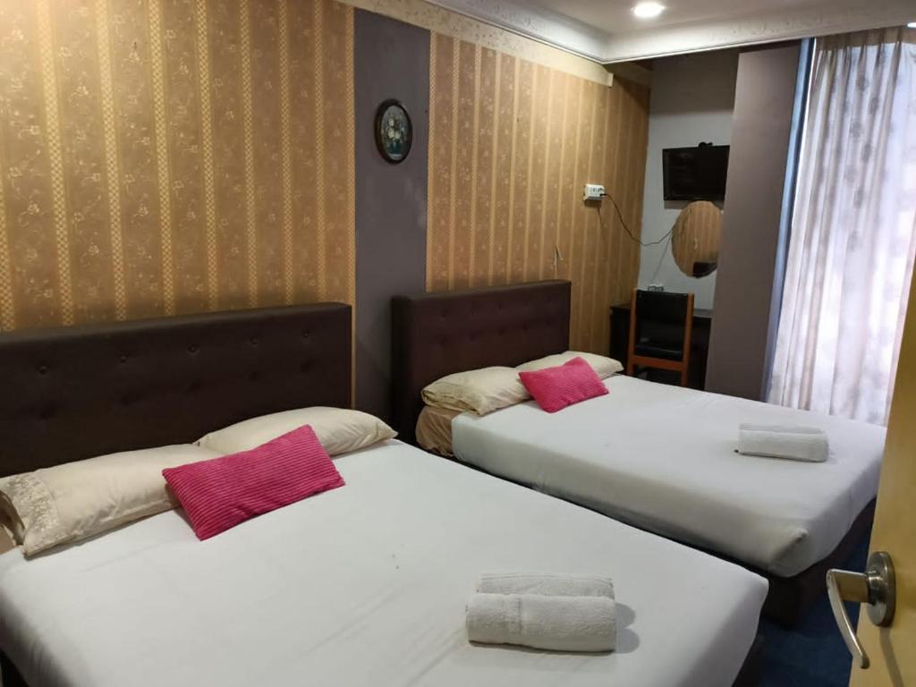two beds in a hotel room with pink pillows at Hotel Tropicanna Pulai Point in Ipoh