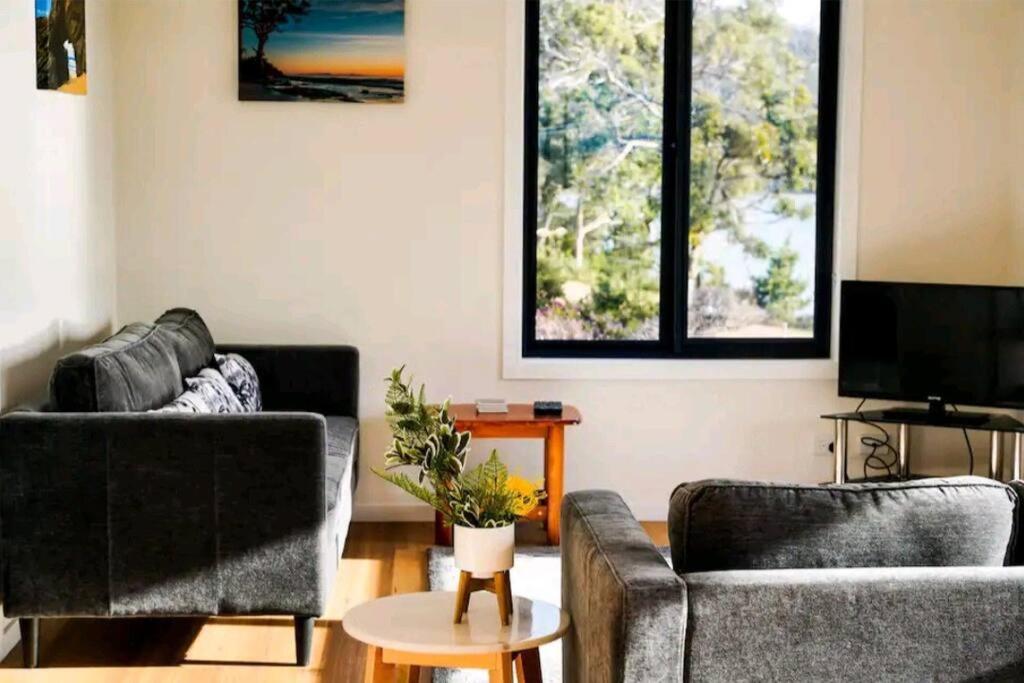 sala de estar con 2 sofás y TV en Rockpool Cottage, en Lunawanna