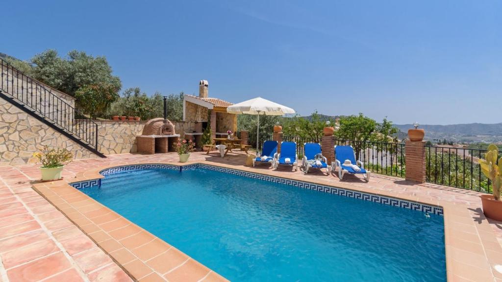 een zwembad met blauwe stoelen en een huis bij Sierra Tejeda - Casa del Valle Alcaucín by Ruralidays in Alcaucín