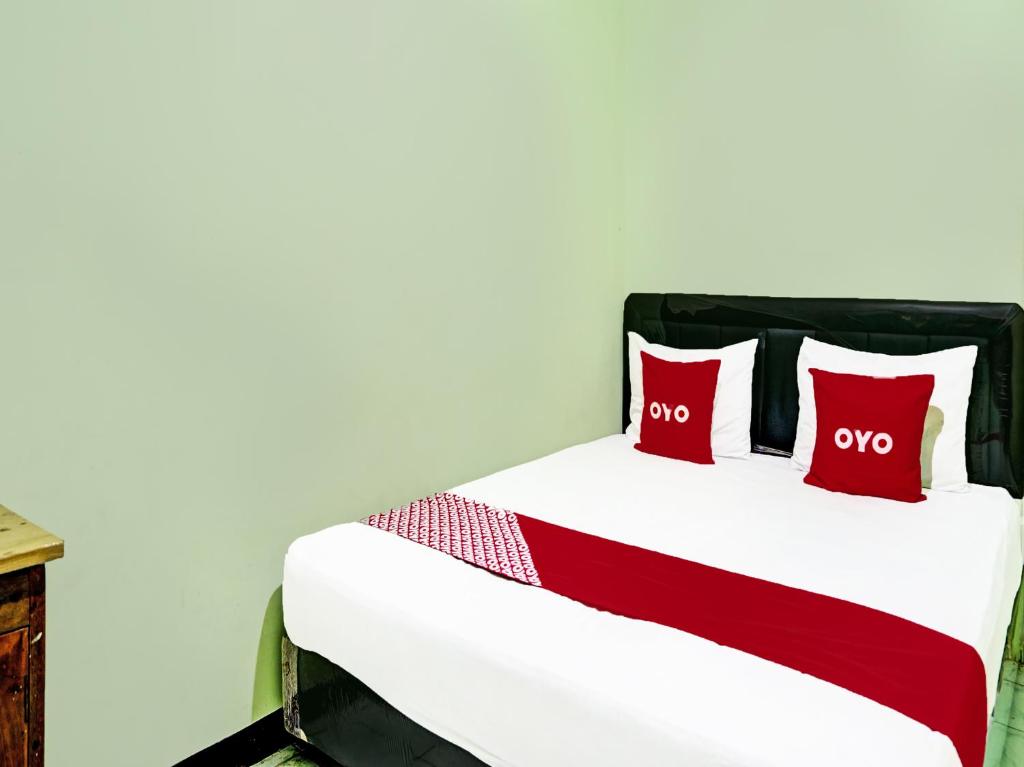 two red pillows on a bed in a room at OYO 2708 Hotel Kemuning Syariah in Ramekasan