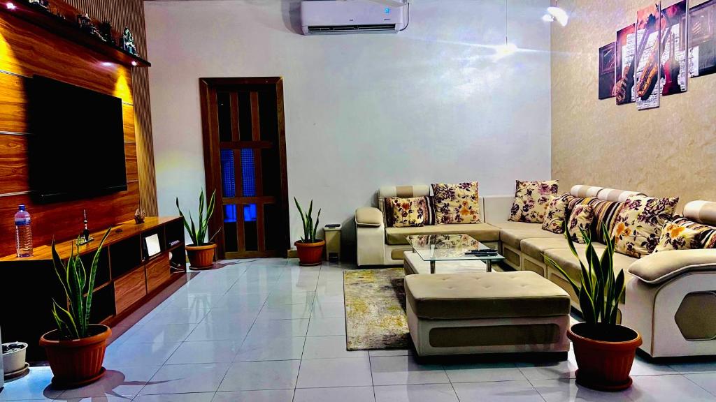 a living room with couches and a flat screen tv at Muladdu Inn in Feydhoo