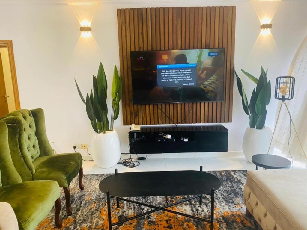 sala de estar con TV y 2 sillas verdes en Elegant 3 bedrooms apartment ikoyi en Lagos