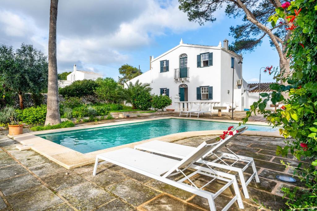 una piscina con due sedie a sdraio e una casa di Villa Torret 46 a Sant Lluís