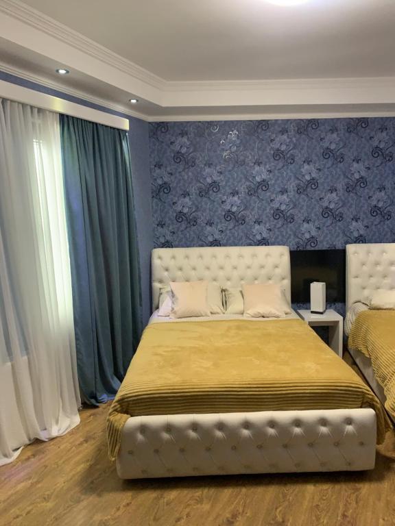 1 dormitorio con 1 cama grande con paredes y cortinas azules en Aisi kutaisi en Kutaisi