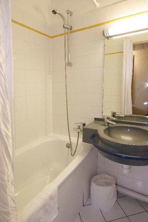 a bathroom with a bath tub and a sink at Kyriad Marne-La-Vallée Torcy in Torcy