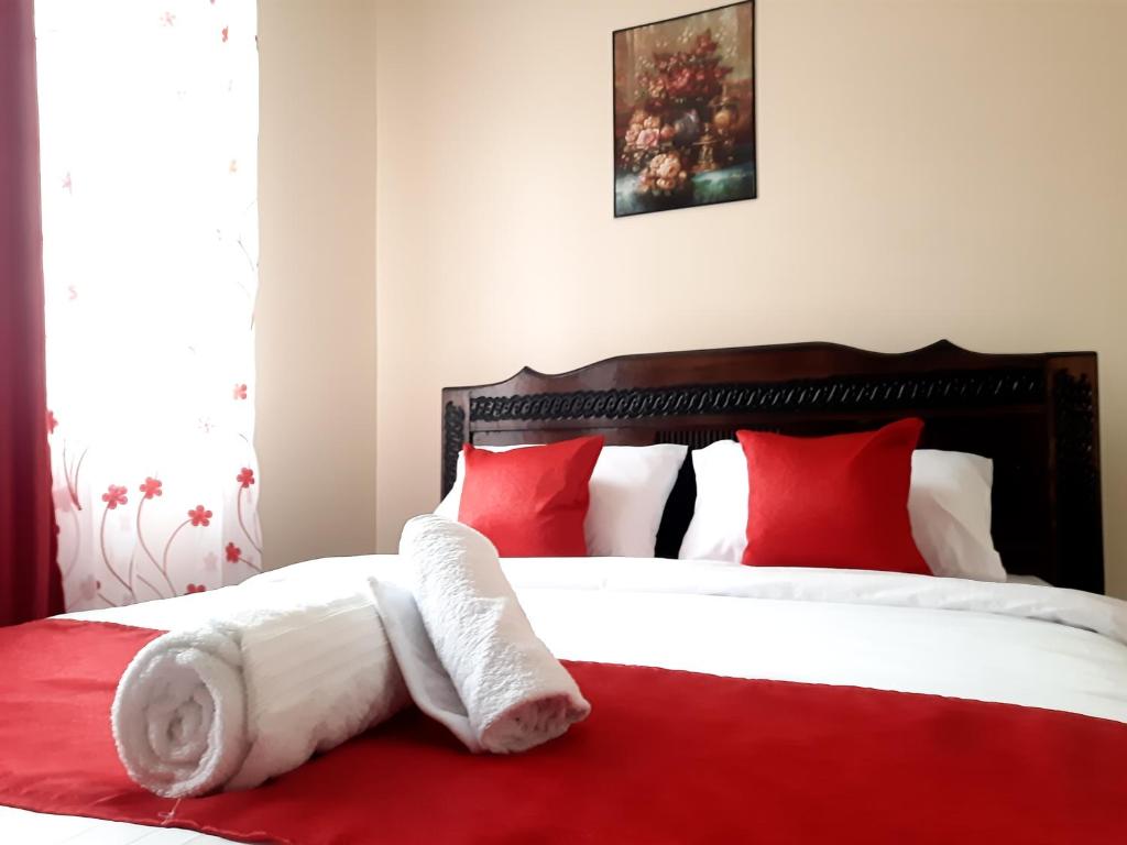 a bedroom with a bed with red and white pillows at Cozy Nest-2 Bedroomed Apartment WiFi ,Netflix close to JKIA in Syokimau