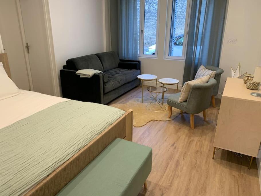 a bedroom with a bed and a couch and chairs at Appartement chaleureux in Dijon