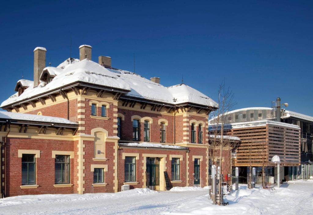 a large brick building with snow on top of it at Lillehammer Stasjonen Hostel in Lillehammer