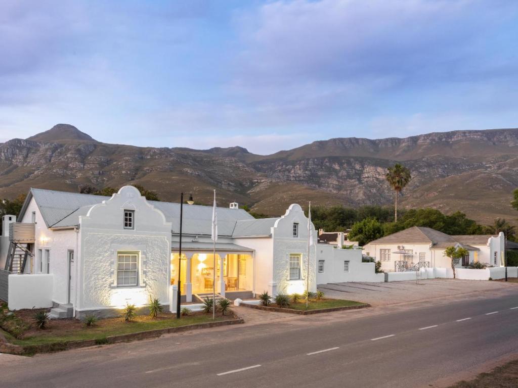 a white house with mountains in the background at Greyton Lodge in Greyton