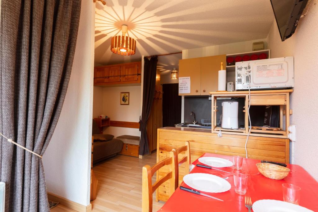 uma cozinha e uma sala de jantar com uma mesa vermelha em Equiria - 1 chambre - balcon em Saint-Léger-les-Mélèzes