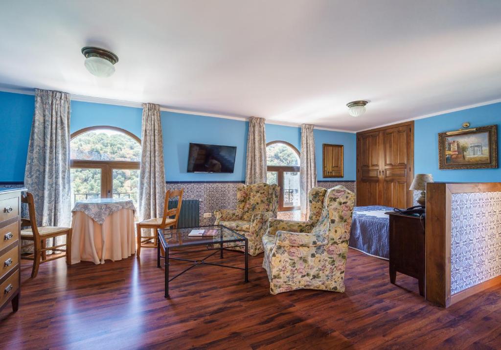 Habitación con paredes azules, cama y sillas. en Hotel Rural Albamanjon en Ruidera