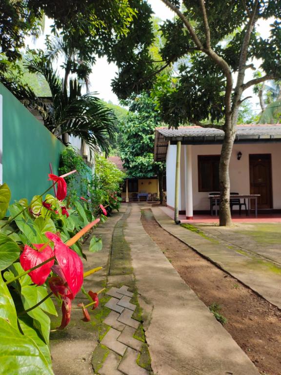 uma passagem em frente a uma casa com flores vermelhas em Ancient Tree em Mirissa