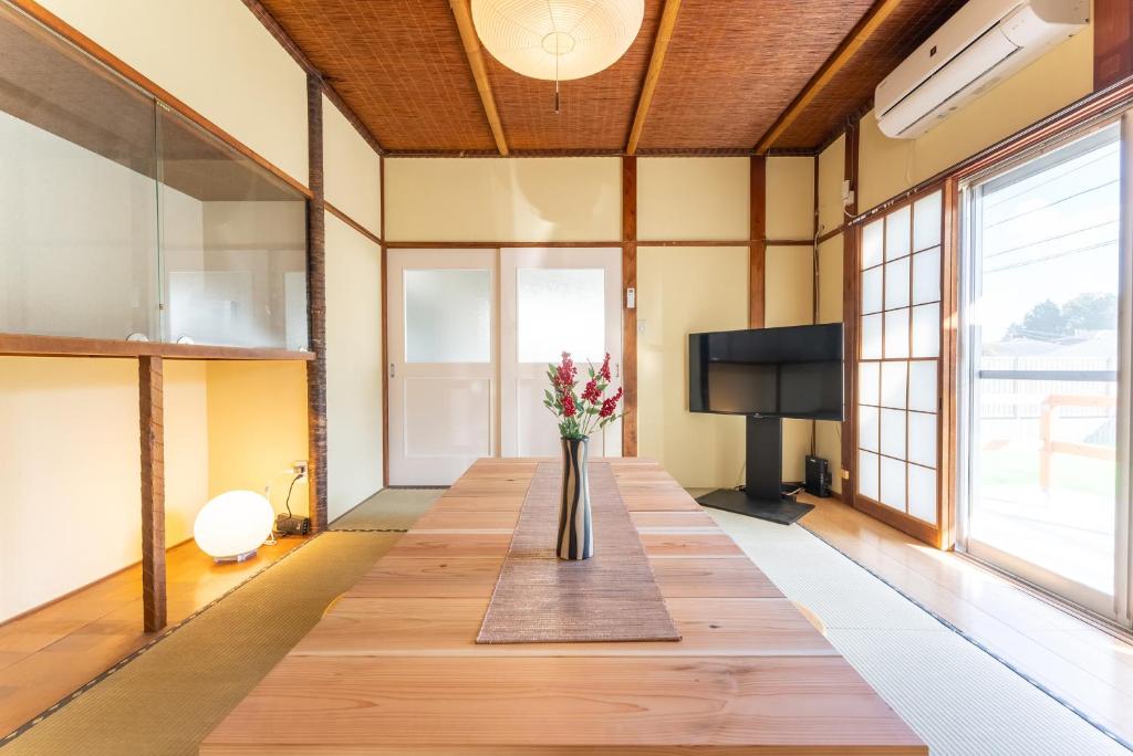 ein großes Zimmer mit einem langen Tisch mit Blumen darauf in der Unterkunft 樹蘭蕉 箱根仙石原 - JYURANSHO Hakonesengokuhara in Hakone