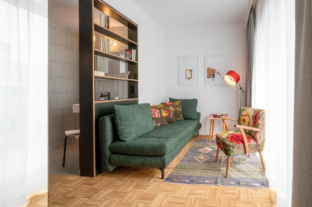 a living room with a green couch and a chair at magdas HOTEL Vienna City - NEW OPENING AUTUMN 2022 in Vienna