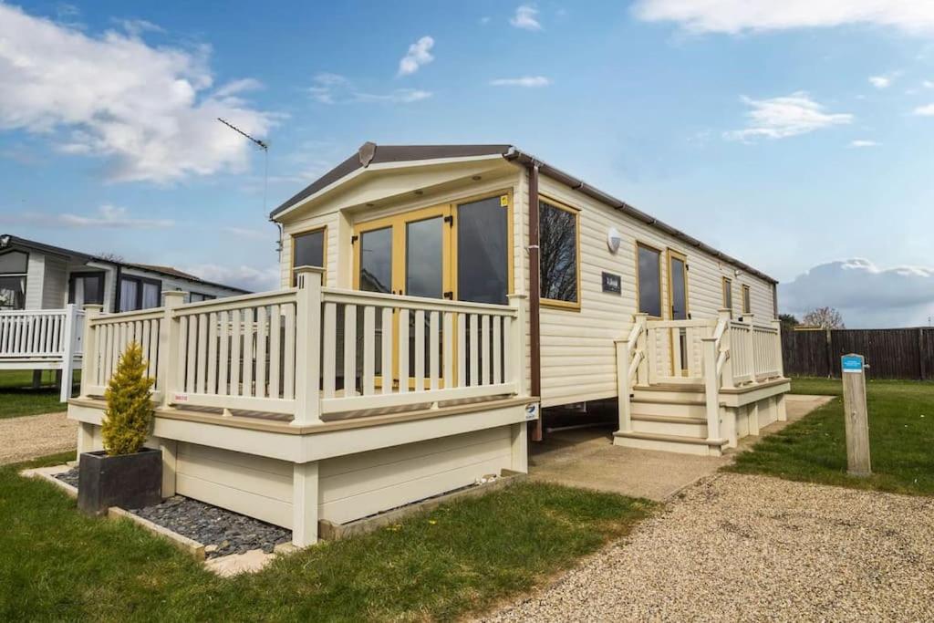 a small white tiny house with a porch at Sunset Drive - Luxury caravan in Great Yarmouth
