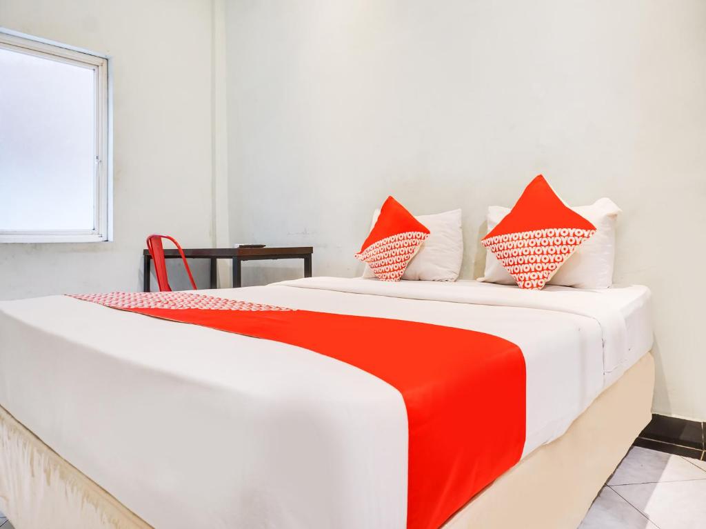 1 cama roja y blanca en una habitación blanca en OYO 3131 Sayang Home Stay en Makassar