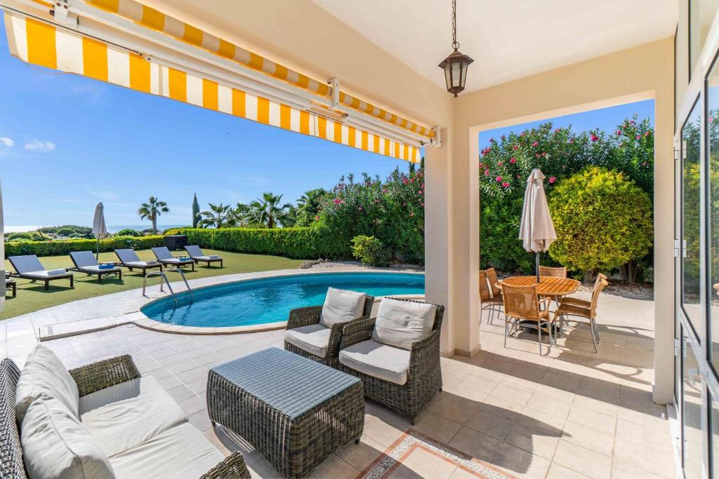 a patio with a pool and chairs and a table at Villa Savoya Sunrise by Ezoria Villas in Coral Bay