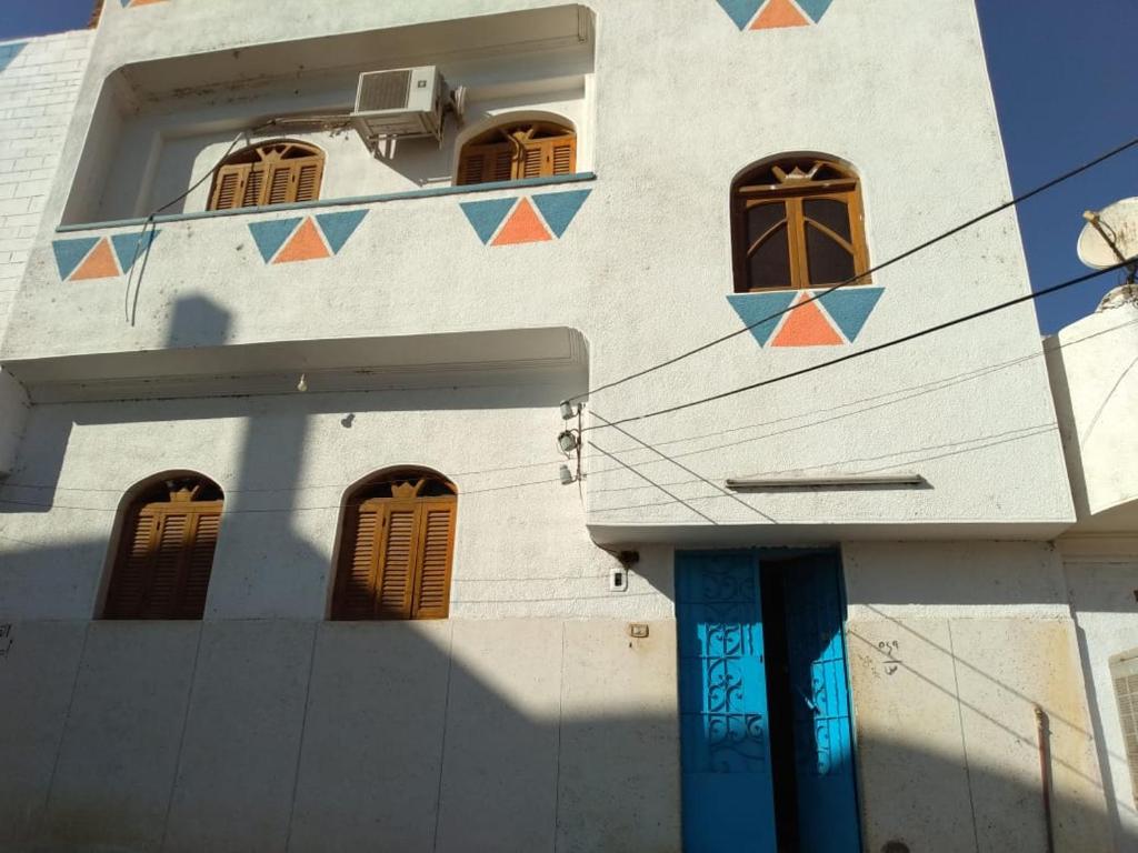 a white building with blue doors and windows at Zekry nubian guest house in Aswan