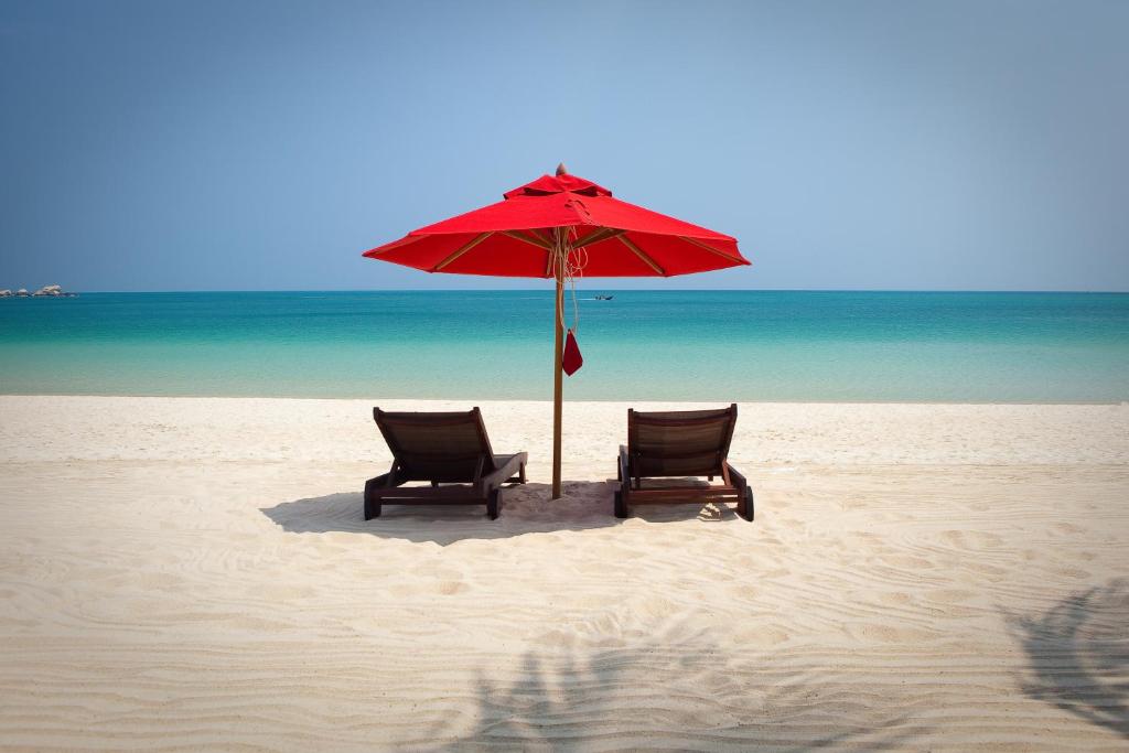 a red umbrella sitting on top of a sandy beach at Anantara Rasananda Koh Phangan Villas in Thong Nai Pan Noi