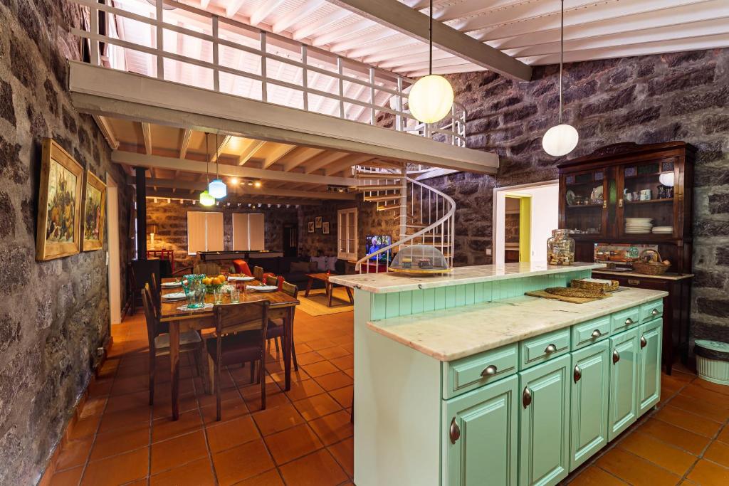 eine Küche mit grünen Schränken und einem Esszimmer in der Unterkunft Adega do Mota in Vila Franca do Campo